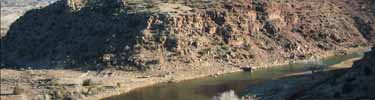 A massive cliff looms above the Chama River in New Mexico.